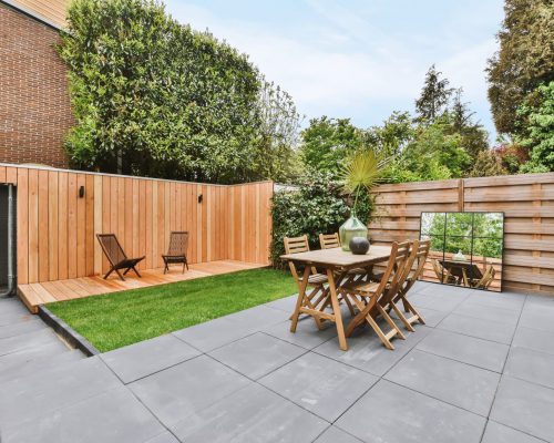 Stylish and well-maintained courtyard of the house with wooden table and chairs and a fresh lawn